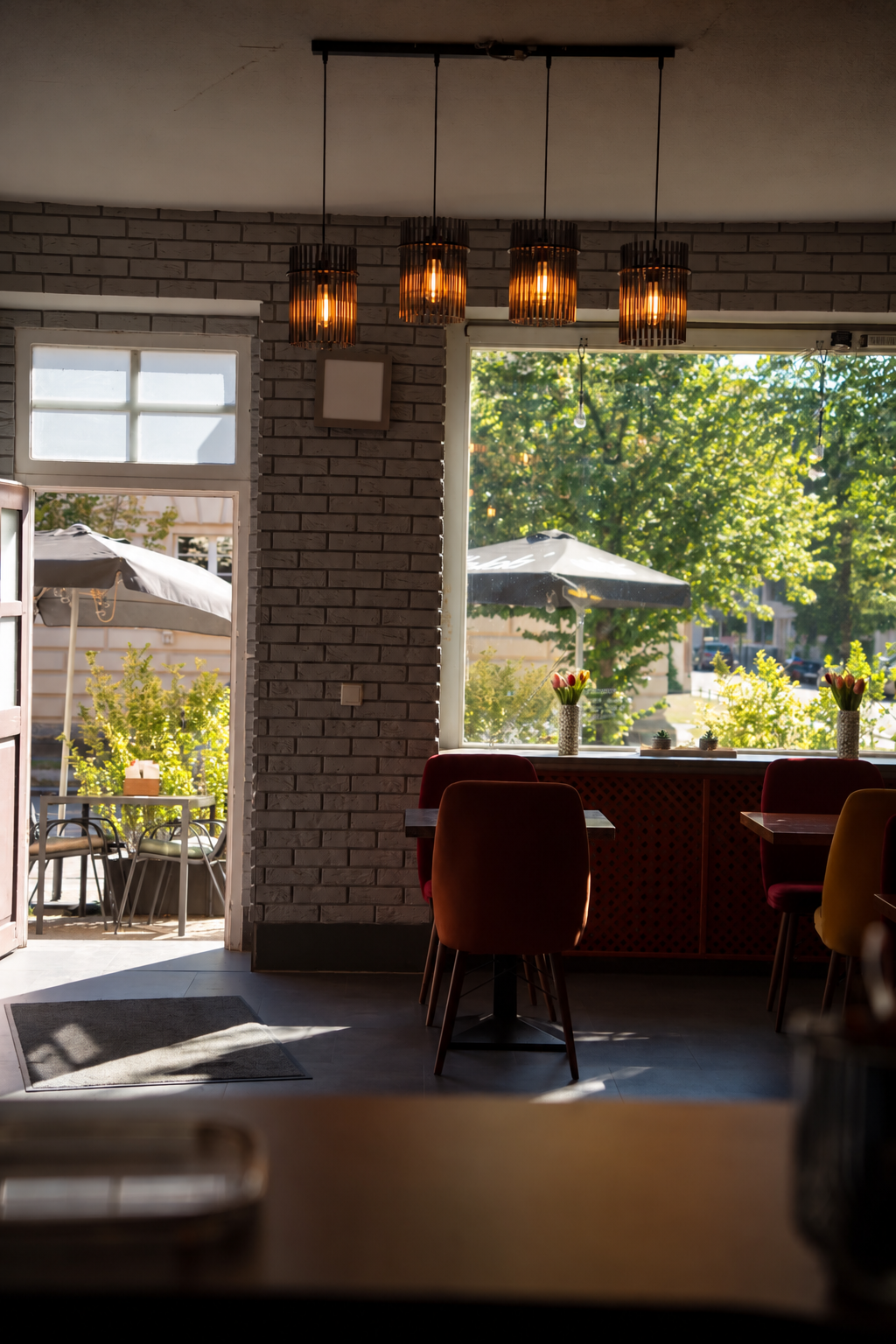 Gemütlicher Gastraum des Burgerfritze in Neuruppin mit Sitzecke, Pendelleuchten und Blick zur Terrasse