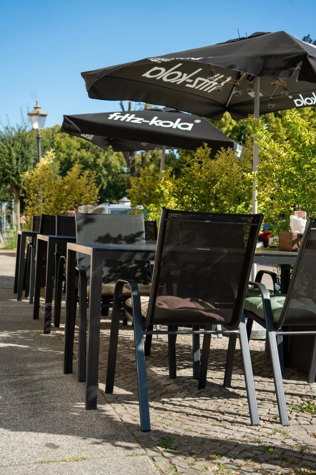 Sonnige Terrasse des Burgerfritze Restaurants in Neuruppin mit Tischen und Schirmen